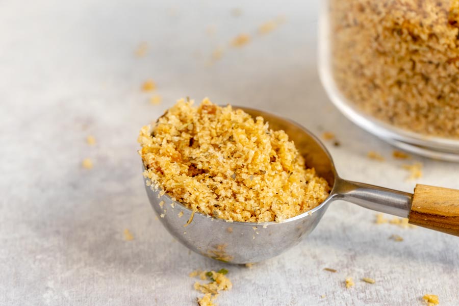 Flaky panko breadcrumbs sitting in a scoop with more crumbs scattered around.