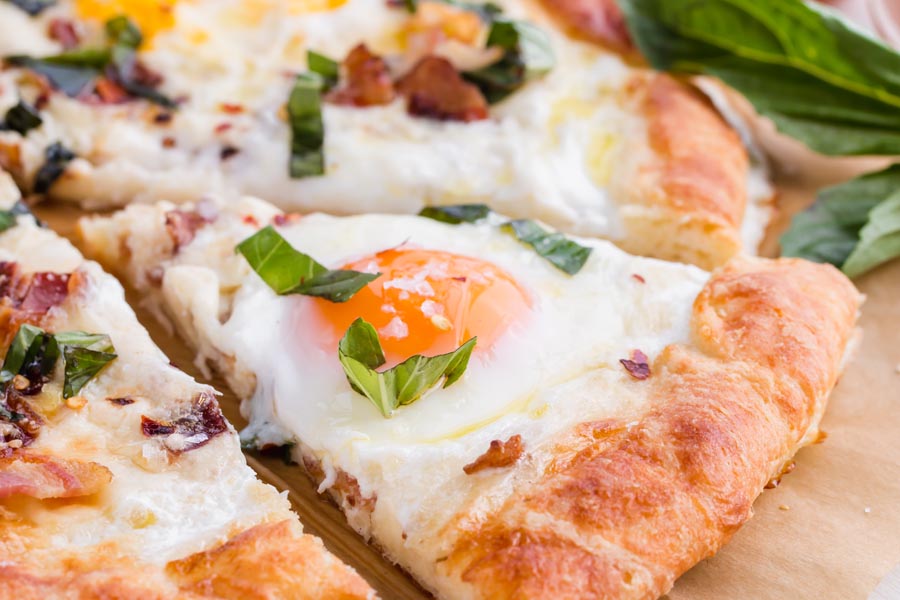 close up view of a slice of breakfast pizza with an egg