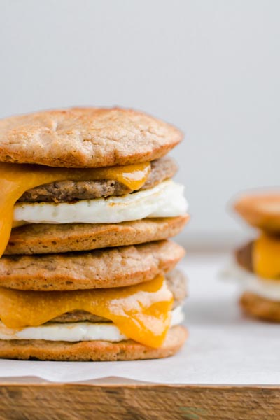 two keto breakfast sandwiches stacked on each other with cheese, sausage patty and egg white