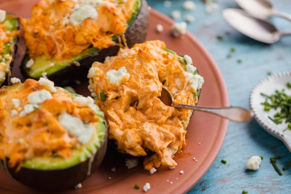 digging into a stuffed avocado filled with buffalo chicken