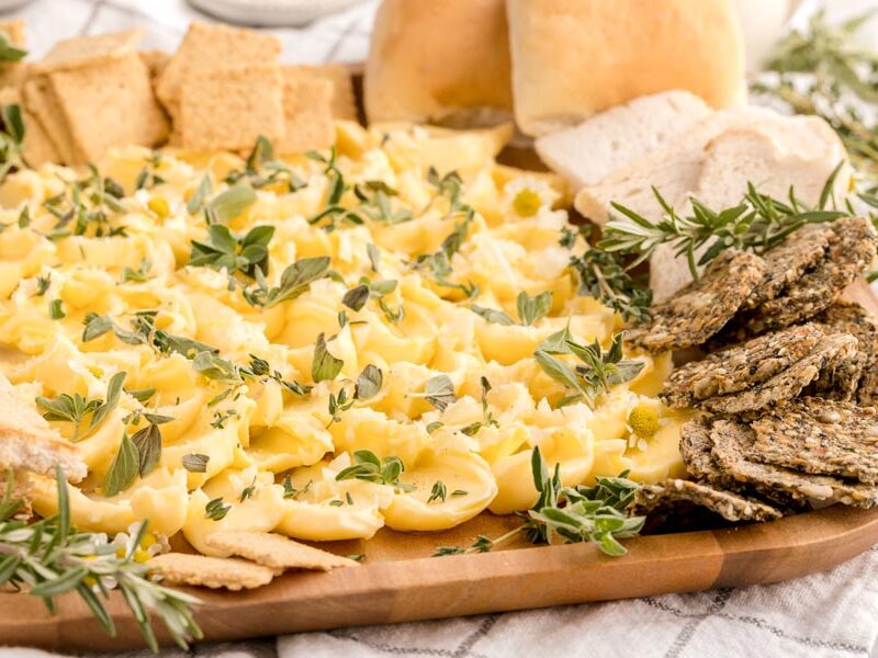 butter spread on a platter in a shape of petals with crackers and bread surrounding the tray