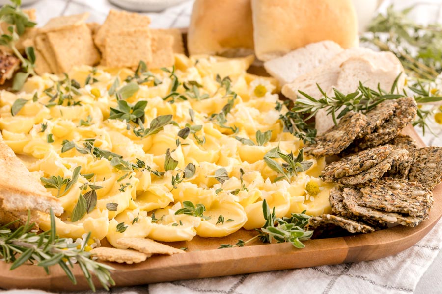 butter spread on a platter in a shape of petals with crackers and bread surrounding the tray