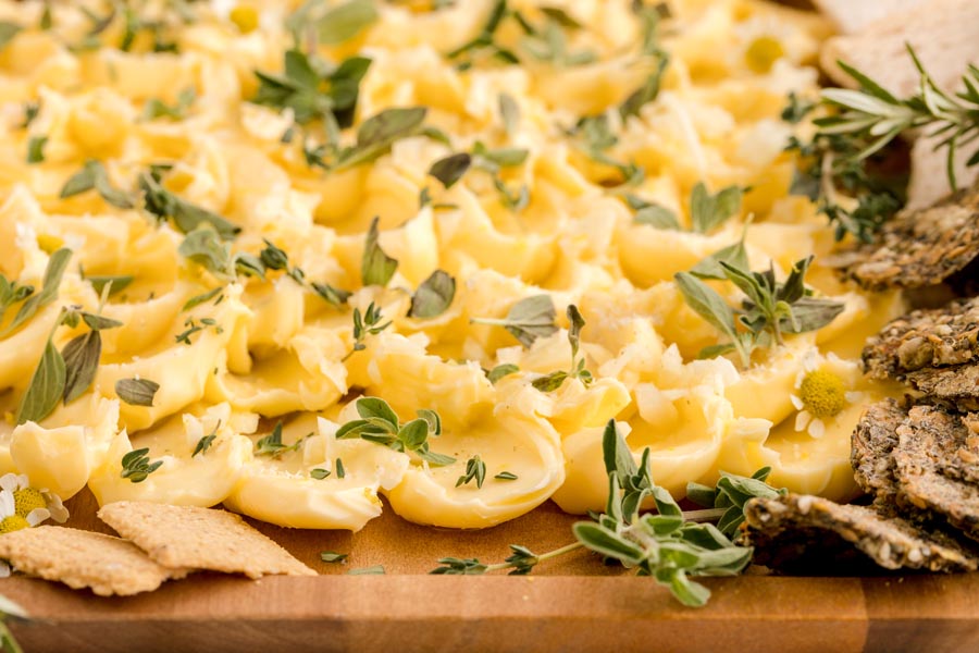 petals of butter on a wooden tray topped with fresh thyme and oregano