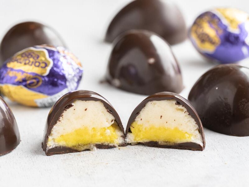 a cadbury eggs sliced in half with other chocolate eggs and foil wrapped eggs behind it