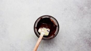 a small bowl with melted dark chocolate and a spatula sitting in it