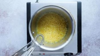 liquid candy boiling in a sauce pan with wire whisk above