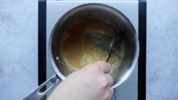 scraping the bottom of a pan to show the caramel is ready to be removed from the heat