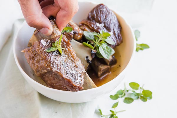 picking up a cooked short rib by the fingers