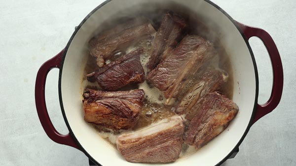 short ribs in dutch oven with broth boiling