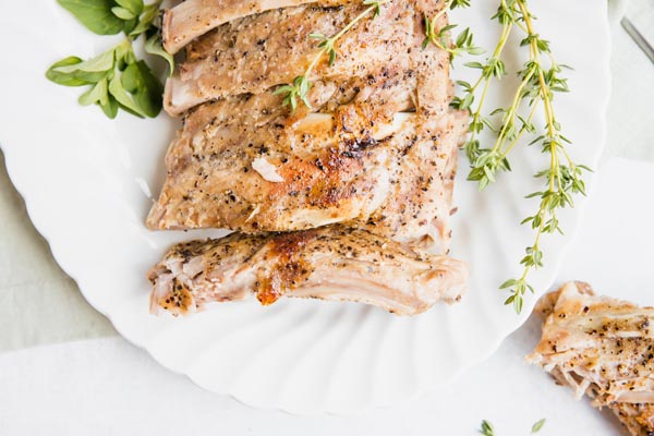 pork ribs on a white plater with some herbs on top