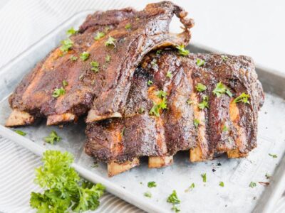 smoked beef back ribs on a baking tray sprinkled with parsley