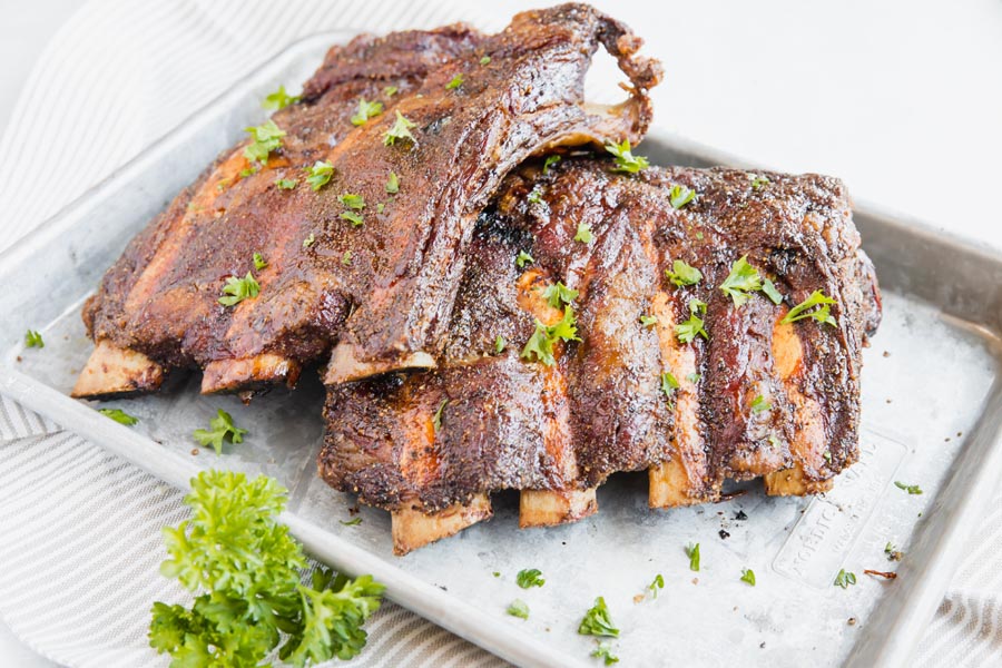 smoked beef back ribs on a baking tray sprinkled with parsley