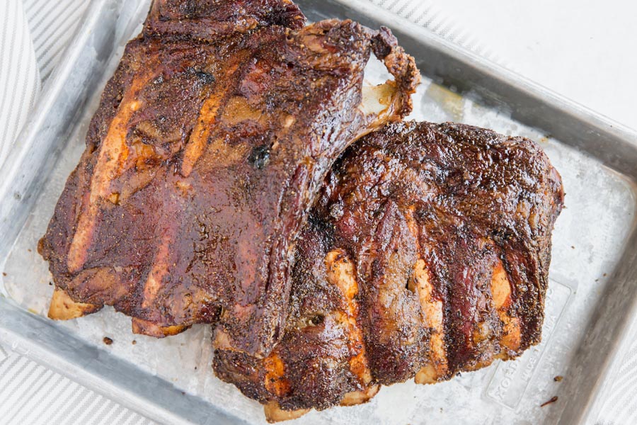 bare dry rubed beef ribs on a metal tray