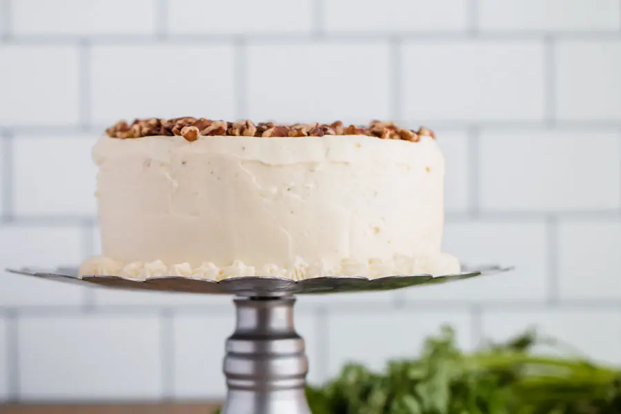 A whole keto almond flour carrot cake on a cake stand.