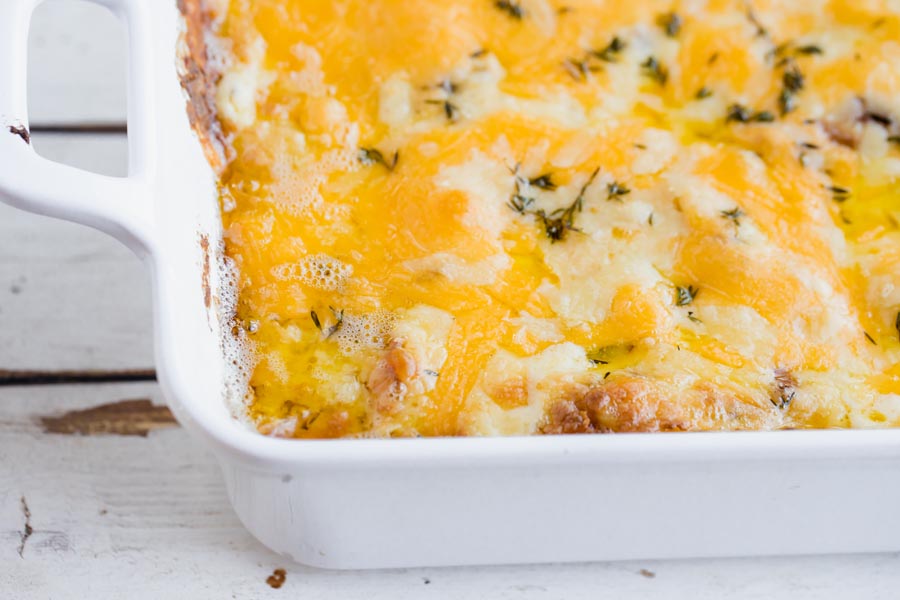 baked cheese cauliflower casserole in a white dish and topped with thyme