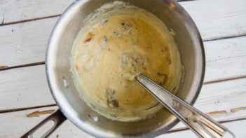 creamy, cheesey sauce in a saucepan with a whisk