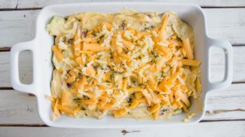 shredded cheese and thyme on top of a casserole