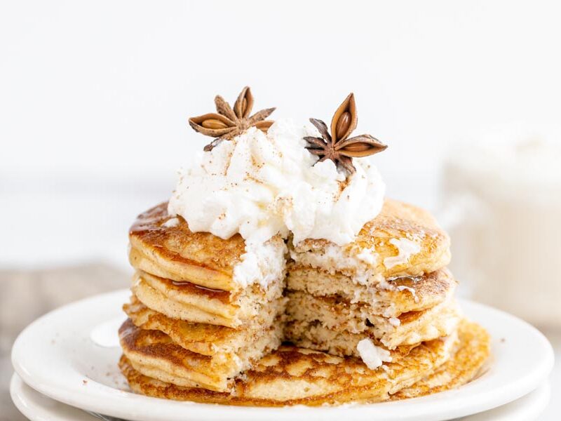 a stack of pancakes with a slice taken out to reveal the fluffy interior of the stack