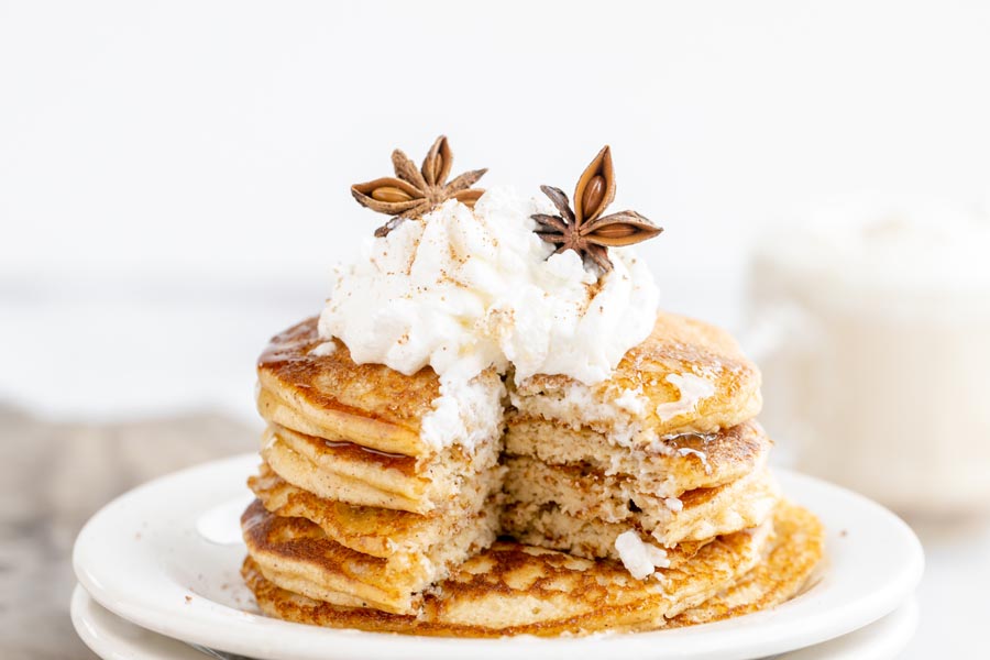 a stack of pancakes with a slice taken out to reveal the fluffy interior of the stack