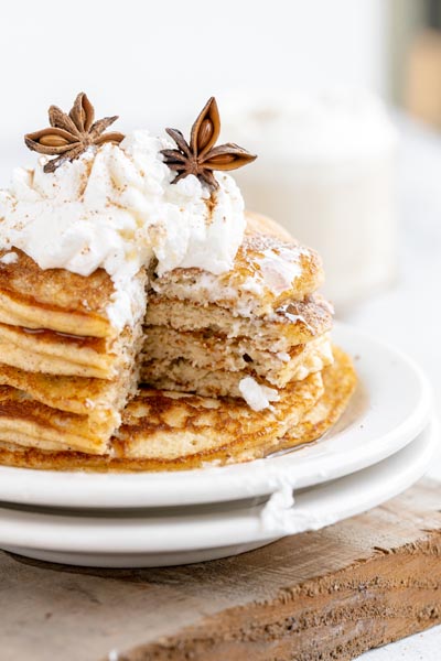 a stack of pancakes on a white plate that has a cut taken out of it