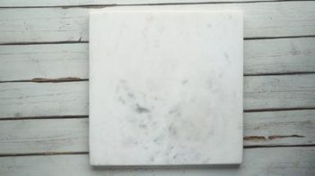 a square white marble slab on a wooden board