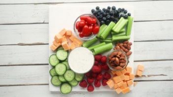 celery, cucumbers, berries on cheese on a marble board