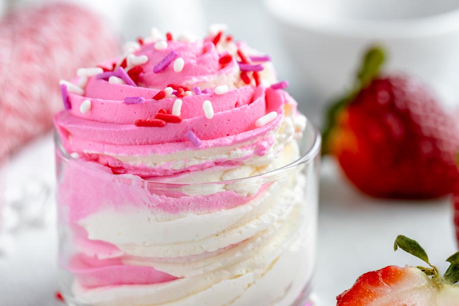 star piped pink and white cheesecake fluff in a small bowl topped with white, red and purple sprinkles