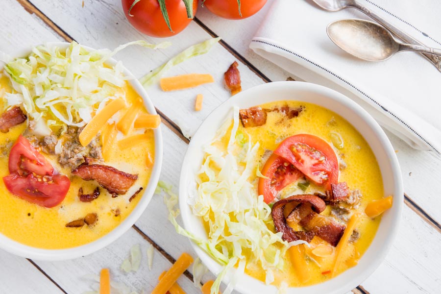 two bowls of cheesey soup with shredded lettuce on top