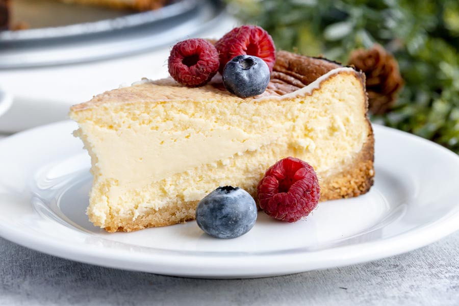 a slice of plain cheesecake on a plate with berries on top