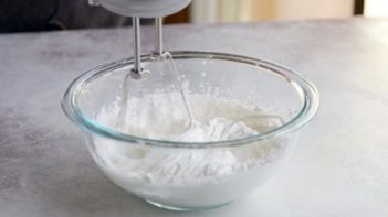 an electric mixer beats whipped cream in a bowl