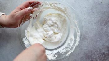 folding whipped cream in a large clear bowl