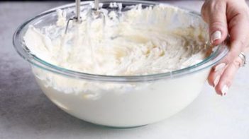 mixing cream cheese batter in a bowl with an electric mixer