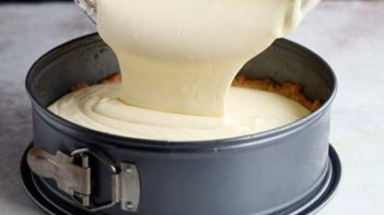 pouring creamy cheesecake filling into a springform pan