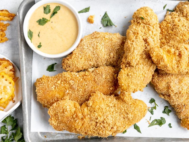 Crispy chicken strips with Chick-fil-A-style dipping sauce on a sheet pan.