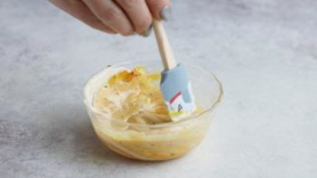 stirring homemade chick-fil-a sauce in a small bowl with a gray spatula