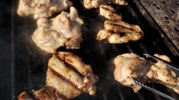 Chicken thighs grilling on a grill plate.