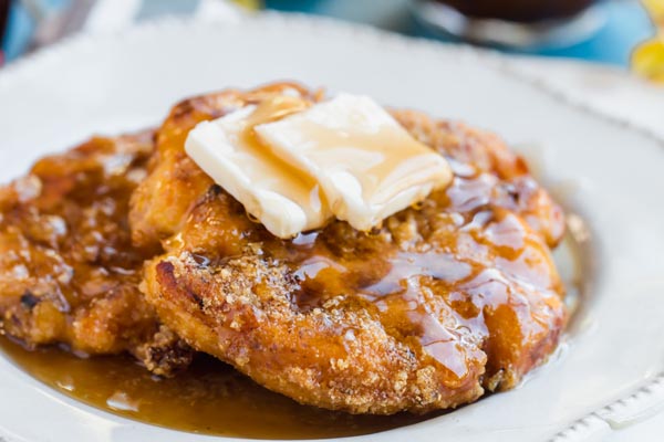 two crispy coated wafles with butter and maple syrup