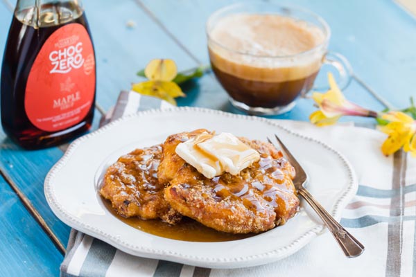 crispy waffles on a plate with coffee and syrup next to it