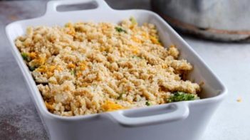 an unbaked casserole topped with a breadcrumb topping in a white dish