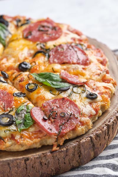 A cheesy, baked chicken crust pizza topped with pepperoni, olives and basil.