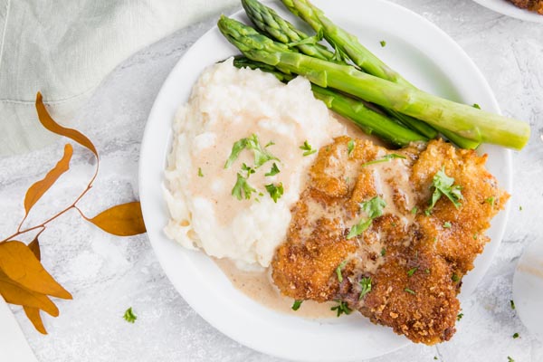 a plate of keto chicken fried steak with a side of mashed cauliflower and green beans