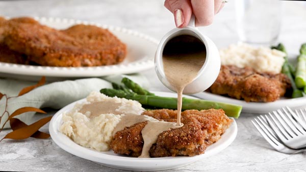 pouring brown gravy on chicken fried steak and mashed cauliflower