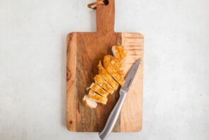 Slice katsu chicken on a cutting board next to a knife.