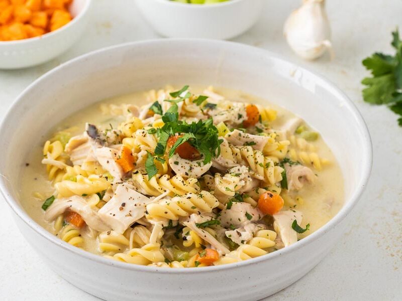 A bowl of chicken noodle casserole topped with parsley and fresh cracked pepper.