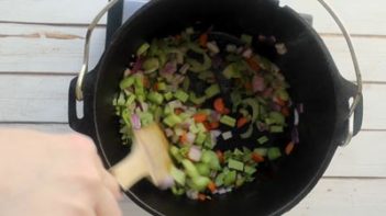 stirring celery, onions and carrots with a wooden spoon
