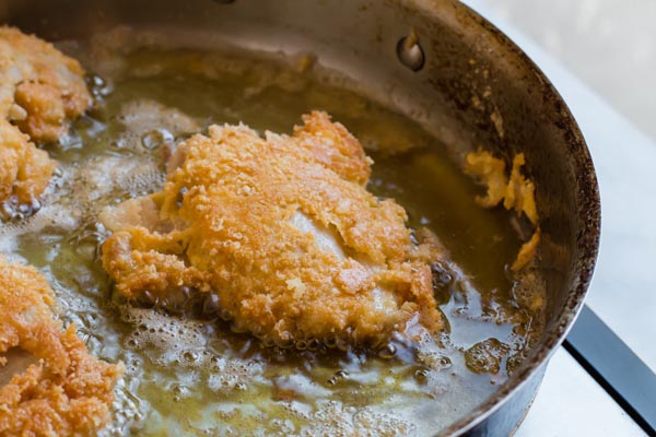 breaded chicken frying in pan