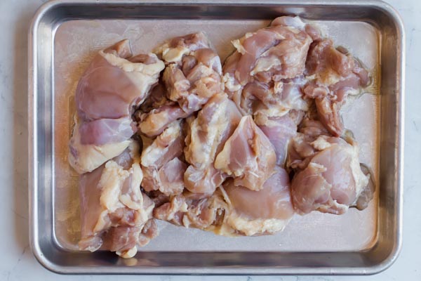 raw chicken cut up and on metal pan
