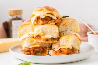 A stack of keto chicken parmesan sliders layered with crispy chicken, marinara sauce, and gooey mozzarella cheese on soft slider buns.