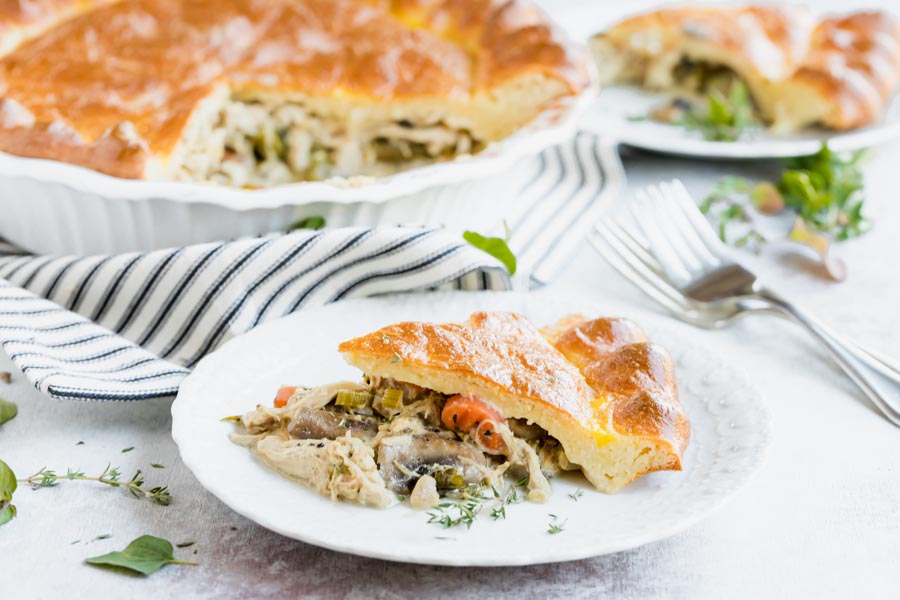 a savory slice of pie on a dinner plate next to forks with another slice on a plate in the background