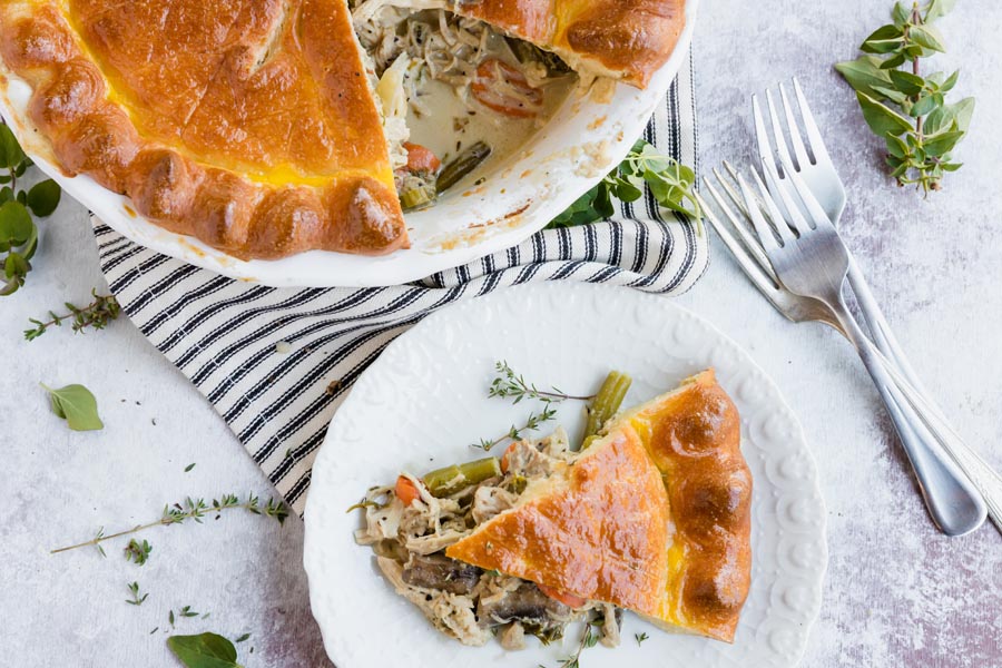 looking down on a slice of pot pie on a plate with the finished pie above it